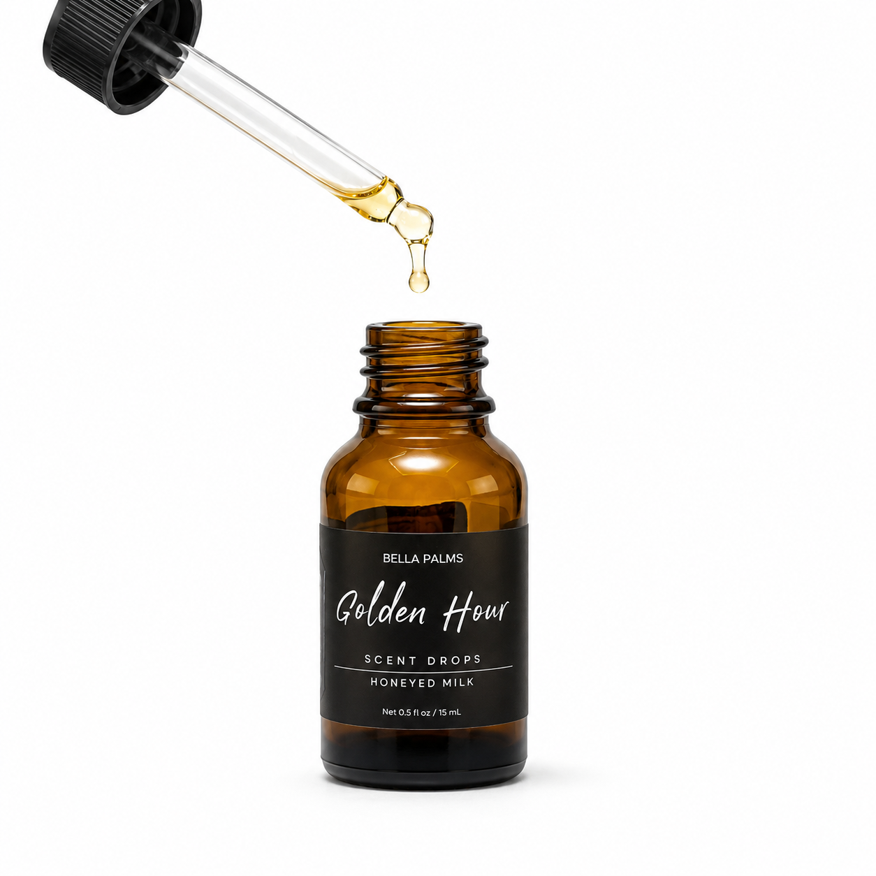 An amber glass dropper bottle labeled Bella Palms Golden Hour Scent Drops Honeyed Milk, with a glass pipette dispensing a drop of golden liquid above the open bottle on a white background.