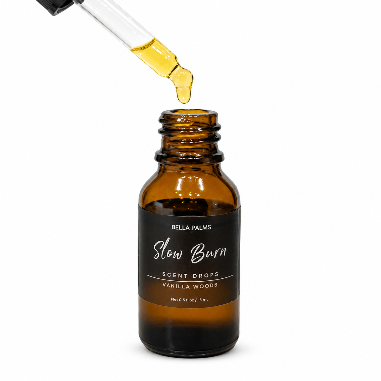 An amber glass dropper bottle labeled Bella Palms Slow Burn Scent Drops Vanilla Woods, with a glass pipette dripping golden oil above the open bottle, on a white background.